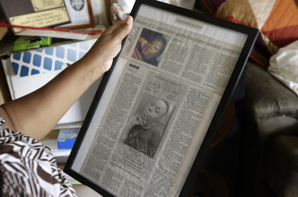 In this photo taken Tuesday, Aug. 6, 2019, Brenda Scurlock is shown in her home in Lumber Bridge, N.C. holding a newspaper clipping about her son's murder. Scurlock's son Avery Scurlock, who used the name Chanel when dressing as a woman in social settings and hoped to have sex reassignment surgery, was found shot to death in June. This death of a transgender person in North Carolina is one of 18 so far this year, and 17 of the victims have been black women. (AP Photo/Gerry Broome)