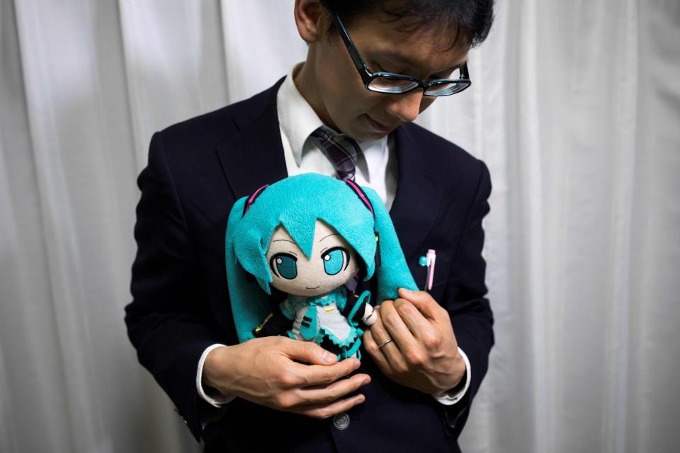 Japanese Akihiko Kondo poses with a doll of Japanese virtual reality singer Hatsune Miku. He "married" an image of the character at an unofficial ceremony which was sanctioned by the holograms creators: AFP/Getty Images