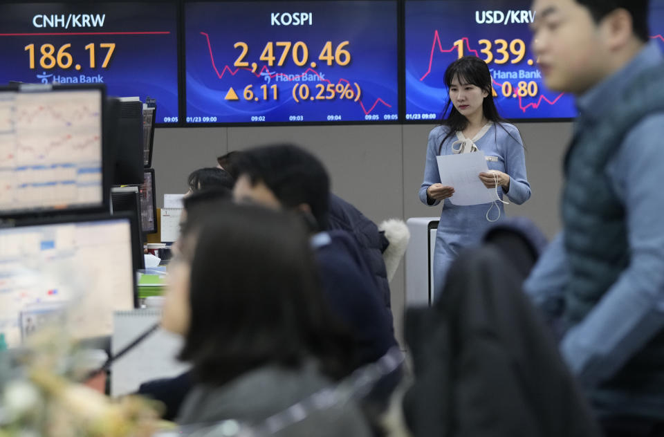 A currency trader passes by the screens showing the Korea Composite Stock Price Index (KOSPI), center, and the foreign exchange rate between U.S. dollar and South Korean won, right, at the foreign exchange dealing room of the KEB Hana Bank headquarters in Seoul, South Korea, Tuesday, Jan. 23, 2024. Asian shares mostly rose Tuesday after Wall Street built on its all-time high reached last week, while Japan’s central bank kept its easy credit policy intact. (AP Photo/Ahn Young-joon)