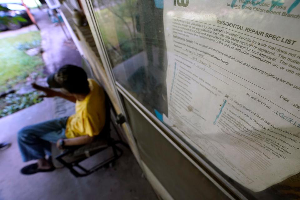 A weathered construction permit remains taped the front door as Mal Moses talks about the damage done to his home by Hurricane Harvey in 2017 and the difficulties he faced to get repairs, Thursday, Aug. 25, 2022, in Houston. A local nonprofit, West Street Recovery, ultimately helped repair his home. (AP Photo/David J. Phillip)