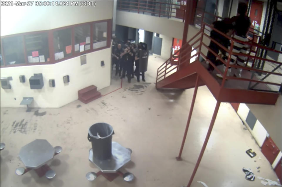 In this Saturday, March 27, 2021, image taken from video released Friday, April 2, 2021, by the Oklahoma City Police Department from the Oklahoma County Detention Center, a jailer is attacked by an inmate, upper right, before being shot and killed by police while holding a homemade knife to the jailer's neck. Police Chief Wade Gourley showed portions of graphic jail video to reporters on Friday, including video that shows inmates beating and stabbing the jailer, whose hands were tied behind his back. (Oklahoma City Police Department/Oklahoma County Detention Center via AP)