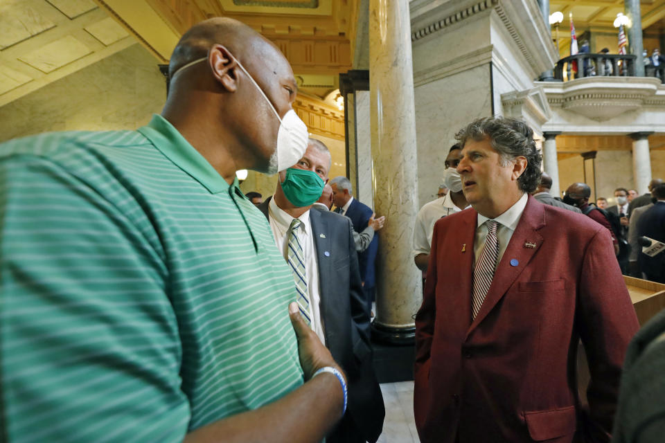 Mississippi State football coach Mike Leach, right, confers with Mississippi Valley State assistant head football coach Willie Totten, left, and Delta State football coach Todd Cooley, center, at the Capitol in Jackson, Miss., Thursday, June 25, 2020, after joining other athletic coaches and their staffs from the state's public universities in a news conference calling for a change in the Mississippi state flag. Several head coaches met with both the lieutenant governor and Speaker Philip Gunn in addition to their lawmakers, to lobby for the change by their respective bodies. The current flag has in the canton portion of the banner the design of the Civil War-era Confederate battle flag, that has been the center of a long-simmering debate about its removal or replacement. (AP Photo/Rogelio V. Solis)
