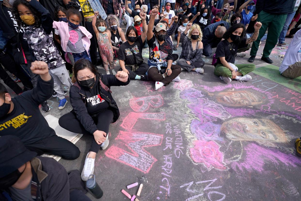 Protesters hold up their fists near a chalk drawing of George Floyd and Daunte Wright at the site where George Floyd was killed, Sunday, April 18, 2021, in Minneapolis.