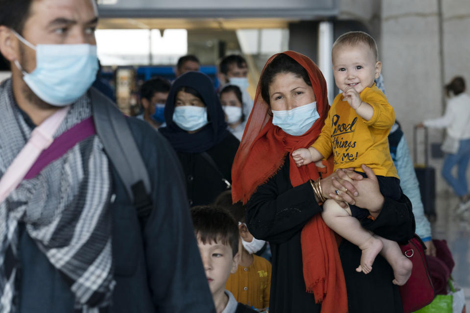 Families evacuated from Kabul, Afghanistan, walk through the terminal before boarding a bus after they arrived at Washington Dulles International Airport, in Chantilly, Va., on Tuesday, Aug. 24, 2021. (AP Photo/Jose Luis Magana)