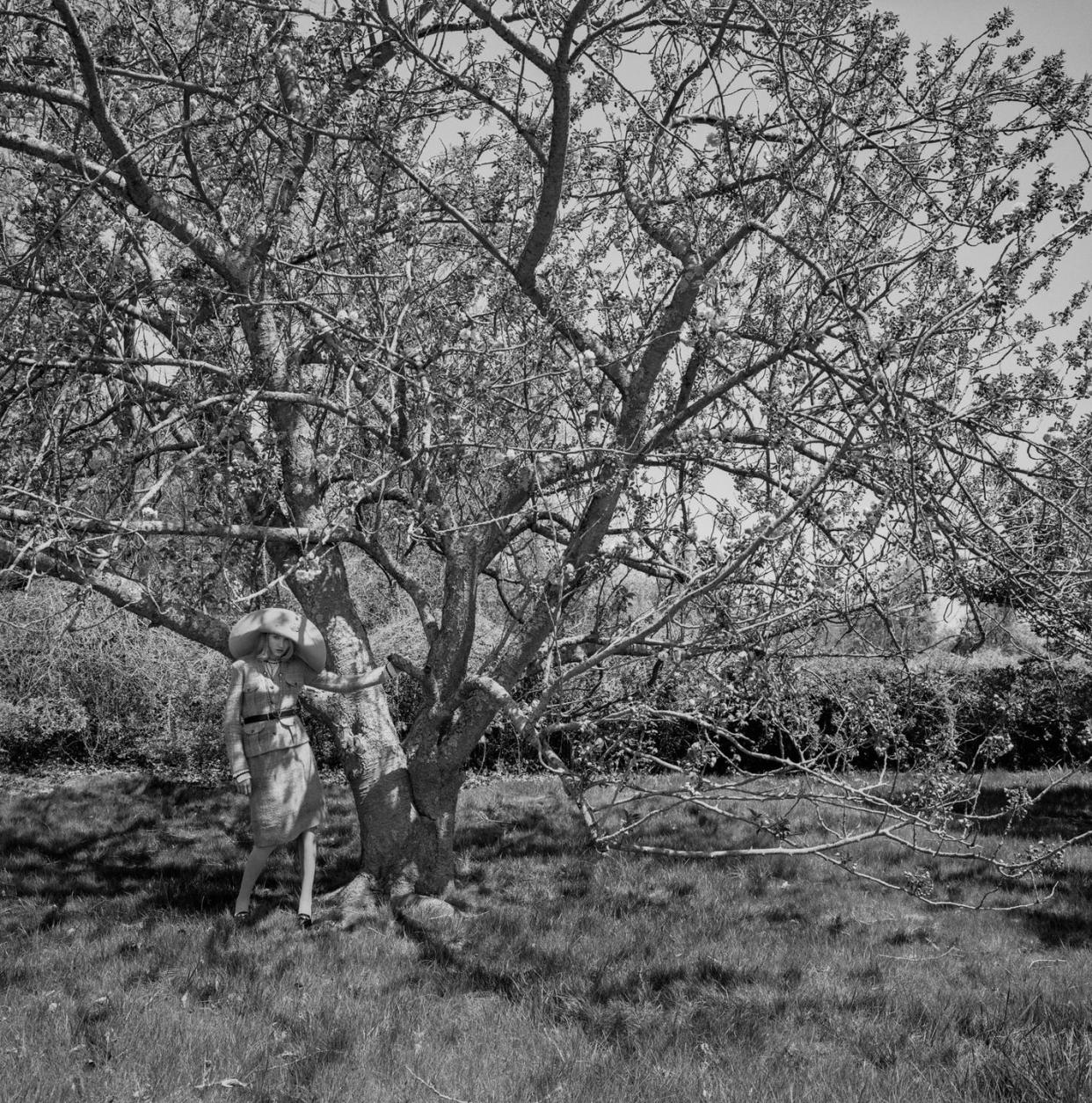 a woman in an oversized hat standing under a tree