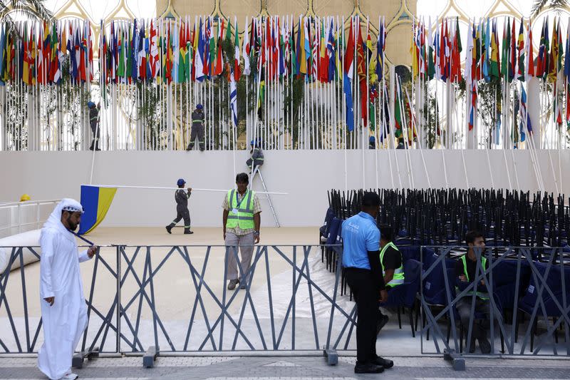 A worker carries a Ukrainian flag in preparation for the opening of U.N.'s COP28 climate summit in Dubai
