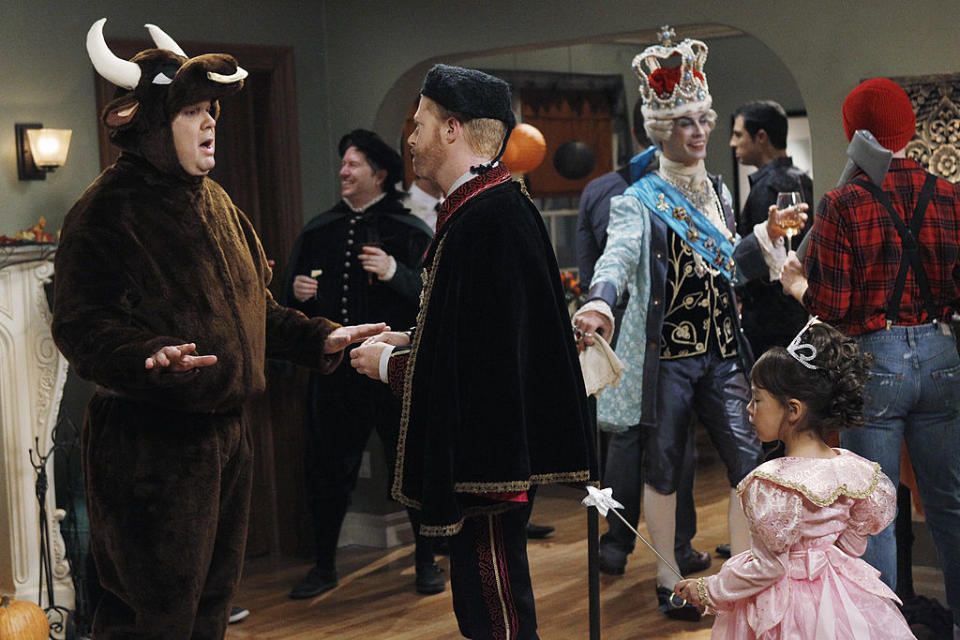 Scene from "How I Met Your Mother" with characters in costumes at a Halloween party. Ted is in a hanging chad outfit, Marshall as a bull, and Lily as a princess