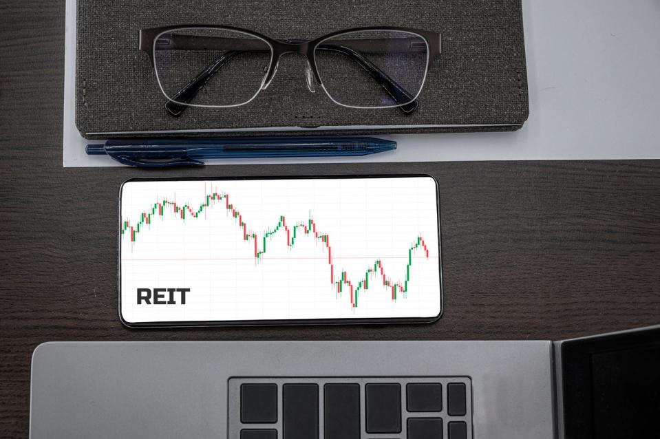 Eyeglasses, a pen, a chart that says REIT, and a bit of laptop.