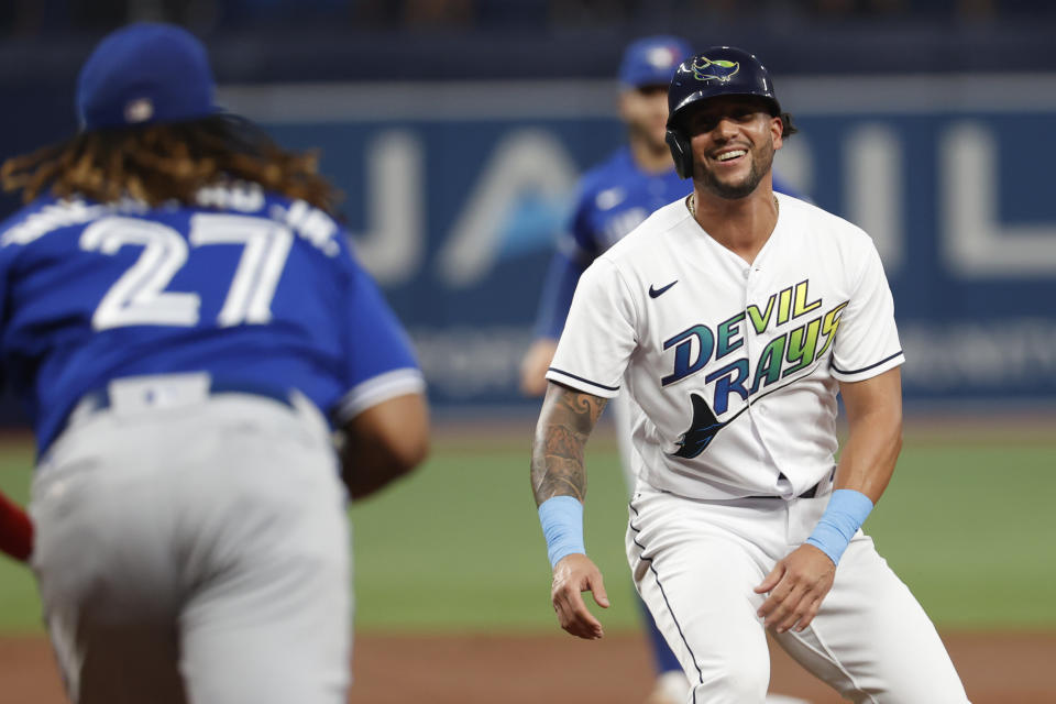 Tampa Bay Rays' David Peralta smiles as he is caught in a rundown, between Toronto Blue Jays first baseman Vladimir Guerrero Jr., foreground, and another player during the second inning of a baseball game Saturday, Sept. 24, 2022, in St. Petersburg, Fla. Peralta was tagged out. (AP Photo/Scott Audette)