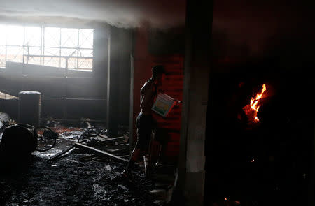 A man uses a bucket of water to help extinguish a fire in burned house where, according to local media, 6 people died, during a protest against Nicaragua's President Daniel Ortega's in Managua, Nicaragua June 16, 2018. REUTERS/Oswaldo Rivas