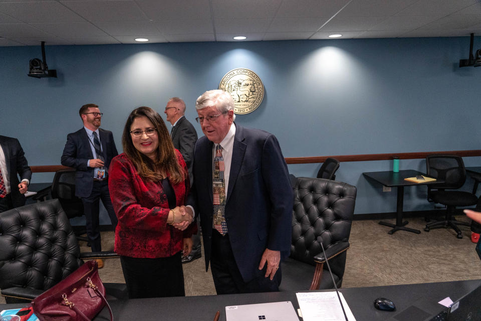 Lea Márquez Peterson, commissioner of The Arizona Corporation Commission, (left) shakes hands with Chairman Jim O'Connor (right) after O'Connor was voted to replace Peterson's position as chair during a meeting at the Arizona Corporation Commission building in Phoenix on Jan. 3, 2023.