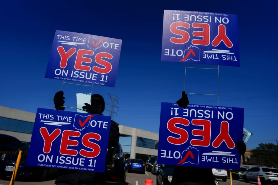 People hold signs urging a vote for a constitutional amendment seeking to protect abortion rights in Ohio in the parking lot of the Hamilton County Board of Elections during early in-person voting in Cincinnati, Thursday, Nov. 2, 2023. (AP Photo/Carolyn Kaster)