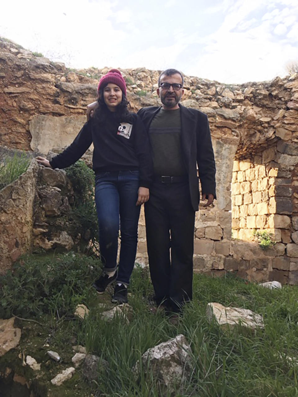 In this March 12, 2020 photo made available by Reem Mousa, Ismail Mousa and his daughter Anisa of Selbyville, Delaware, pose for a photograph while sightseeing near the Palestinian village of Qaryout in the West Bank. Mousa and his daughter found themselves stranded and separated from each other after their travels plans and efforts to return home were thwarted because of the coronavirus pandemic. (Reem Mousa via AP)