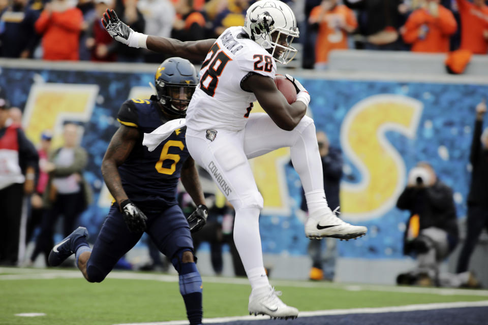 Oklahoma State wide receiver James Washington (28) runs for a touchdown while being defended by West Virginia safety Dravon Askew-Henry (6) during the first half of an NCAA college football game, Saturday, Oct. 28, 2017, in Morgantown, W.Va. (AP Photo/Raymond Thompson)