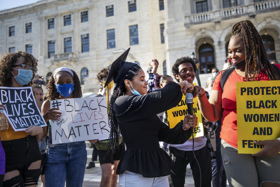 Najeli Rodriguez, 18, center, wearing her cap from her high school graduation this year, fist bumps Amanda Toussaint, during a youth organized Juneteenth protest outside the Statehouse Friday, June 19, 2020, in Providence, R.I. Juneteenth commemorates when the last enslaved African Americans learned they were free 155 years ago. Now, with support growing for the racial justice movement, 2020 may be remembered as the year the holiday reached a new level of recognition. (AP Photo/David Goldman)