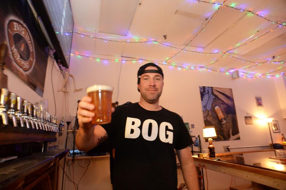 Rob Cormier holds up a beer at Bog Iron Brewing in Norton in this 2021 file photo.