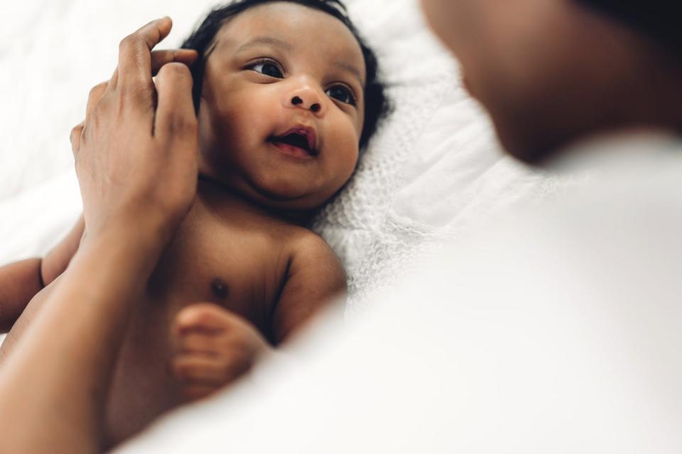 A mother playing with adorable little baby in a white bedroom.