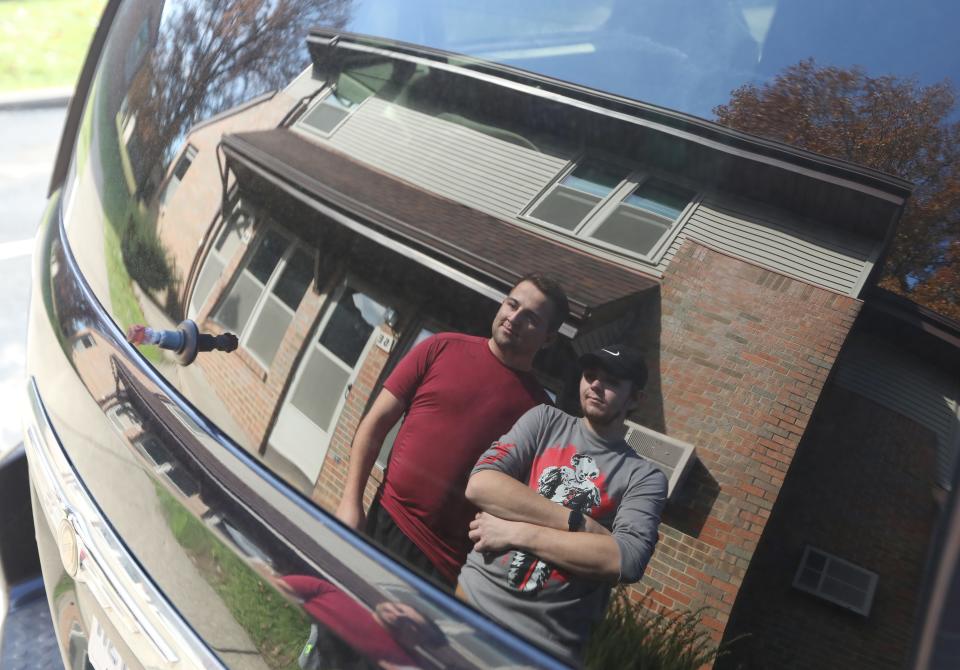Clay Whissen, 23, and Isaac Cook, 20, reflected in the rear window of the van they lived in for three months, parked outside their new apartment in Roseville.