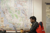 Senior program analyst Siva Jasti works next to a map of California in the Pacific Gas & Electric (PG&E) Emergency Operations Center in San Francisco, Thursday, Oct. 10, 2019. More than 1.5 million people in Northern California were in the dark Thursday, most for a second day, after the state's biggest utility shut off electricity to many areas to prevent its equipment from sparking wildfires as strong winds sweep through. (AP Photo/Jeff Chiu)