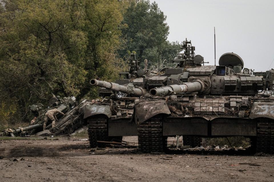 A Ukrainian soldier scavenges one of three abandoned Russian T-90M tanks.