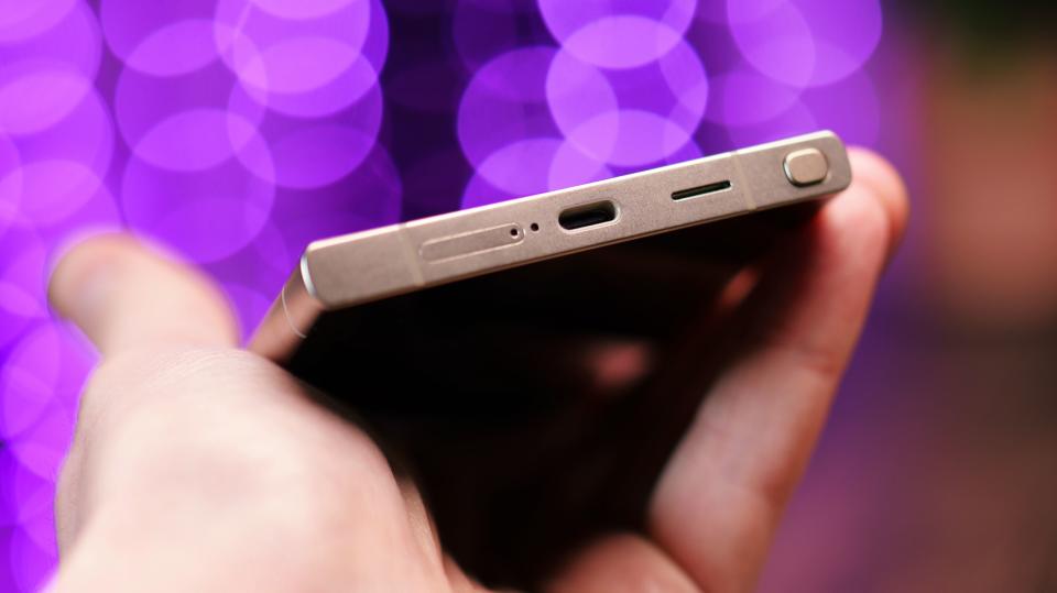 USB-C port on a Samsung Galaxy S24 Ultra phone held in a hand with purple lights blurred in the background