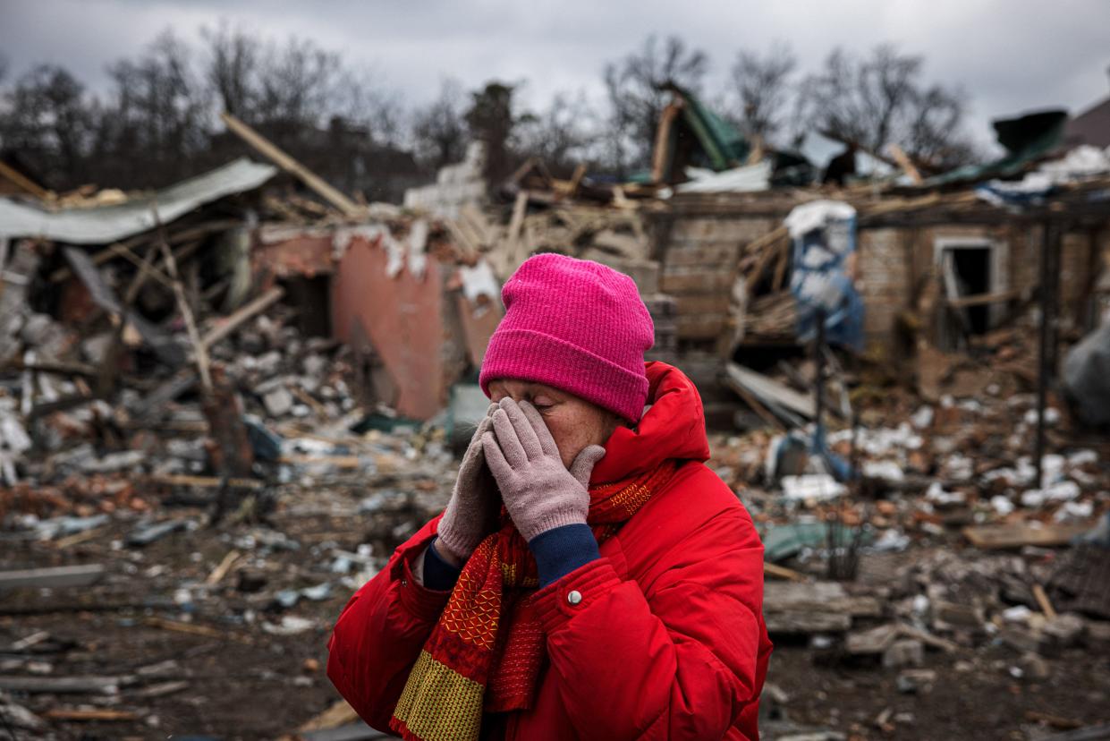 Irina Moprezova covers her face as she stands in front of a bombed-out house in Irpin, northwest of Kyiv, Ukraine. on March 13, 2022. (Dimitar Dilkoff/AFP via Getty Images)