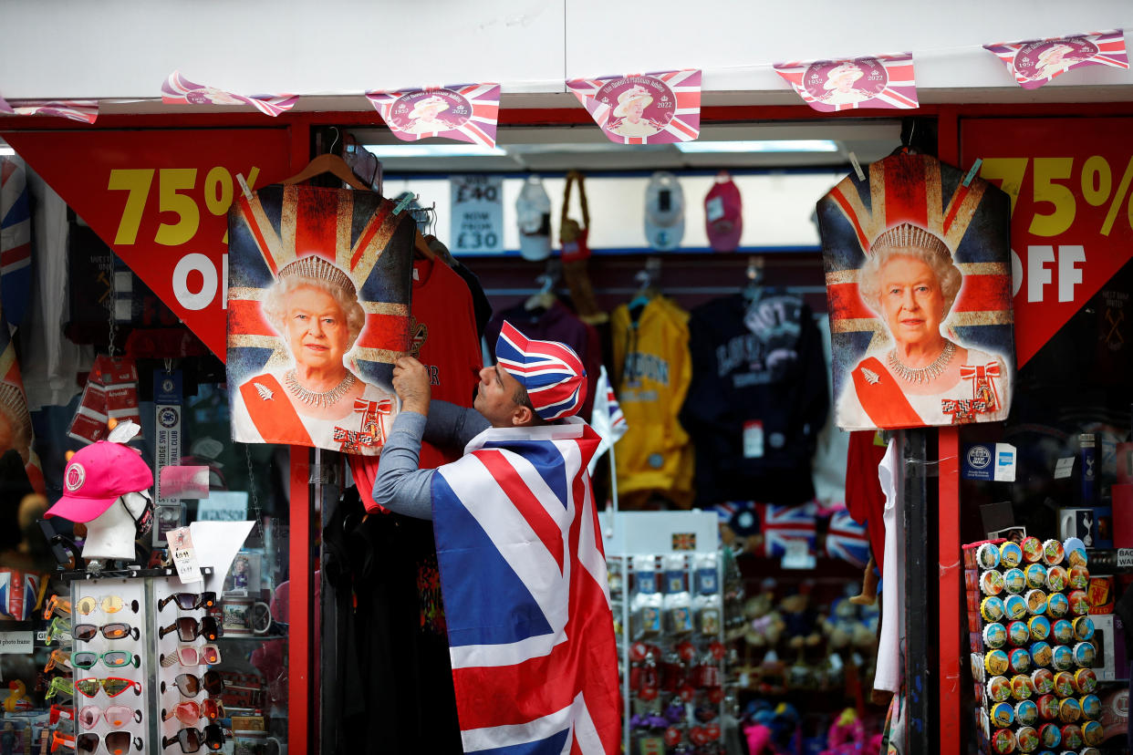 A man wearing a Britain's flag hangs a product with depiction of Queen Elizabeth