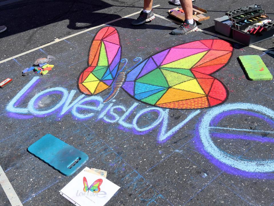 An chalk art creation by artist Robert Mott of Harrisonburg features a butterfly with the words "love is love" on East Beverley Street at the Staunton Pride festival in downtown Staunton on Saturday, Oct. 6, 2018.