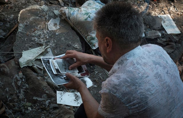 Local resident collects photos of his family left under the rubble after Russian shelling in Mykolaiv, Ukraine, on Wednesday