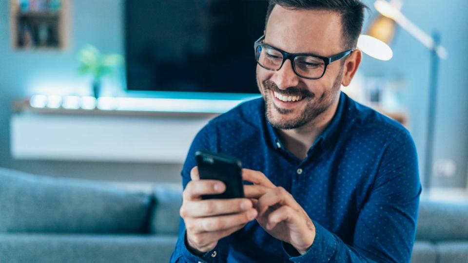 A man smiles while looking at his phone