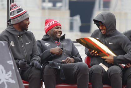 Ohio State football quarterbacks J.T. Barrett, left, Cardale Jones and Braxton Miller look at the College Football Playoff national championship trophy during a celebration of the Buckeyes' national championship at Ohio Stadium in Columbus, Ohio, Saturday, Jan. 24, 2015. (AP Photo/Paul Vernon)
