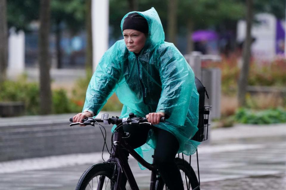 A cyclist travels through Centenary Square in Birmingham during a rainy morning (PA)