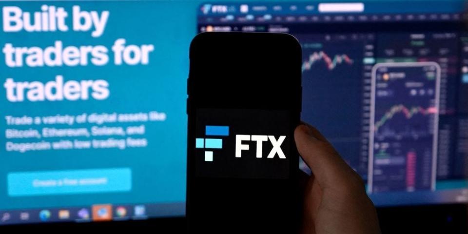 Illustration photo shows a smart phone screen displaying the logo of FTX, the crypto exchange platform, with a screen showing the FTX website