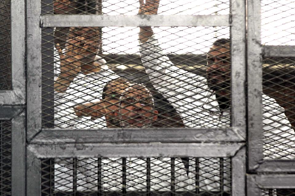 Leader of Egypt's Muslim Brotherhood Mohammed Badie, bottom center, and senior Brotherhood figurer Salah Soltan, right, gesture, during an appearance at a courtroom in Cairo, Egypt, Tuesday, April 1, 2014. Badie has called from his cage on judges to fight against smearing their profession. Badie appeared in court Tuesday for the opening of a new trial in which he and 50 members of the group are facing charges ranging for threatening to destabilize the country to plotting to kidnap the country’s former powerful military chief. (AP Photo/Mohammed Abu Zaid)