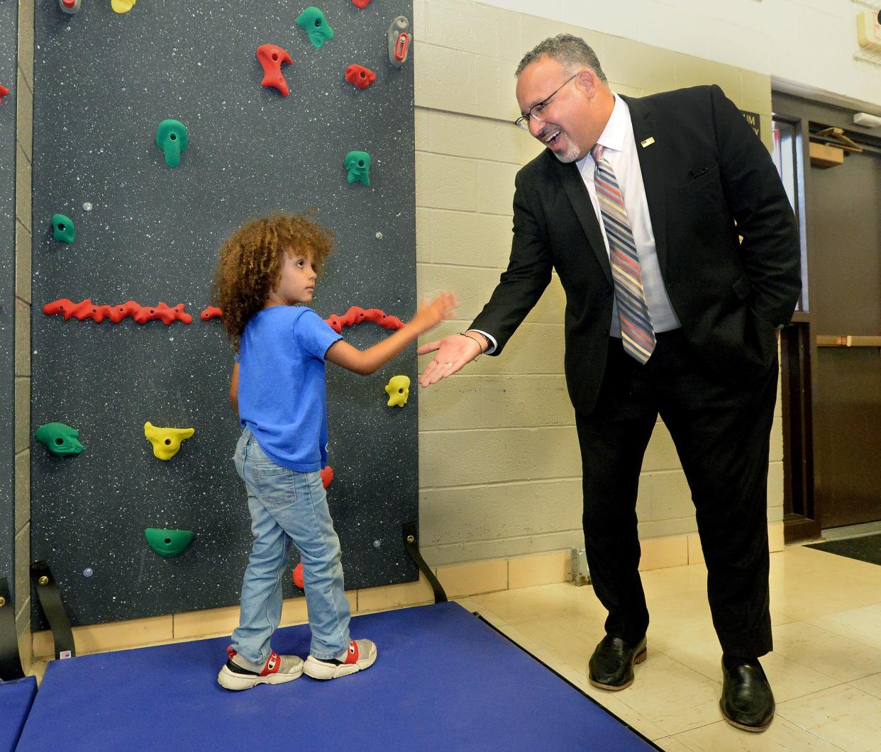 U.S. Secretary of Education Miguel Cardona, right, gets a low five from Torryn Dixon, 5, during Cardona's stop at Fairview Elementary School in Springfield Wednesday, Sept. 6, 2023.