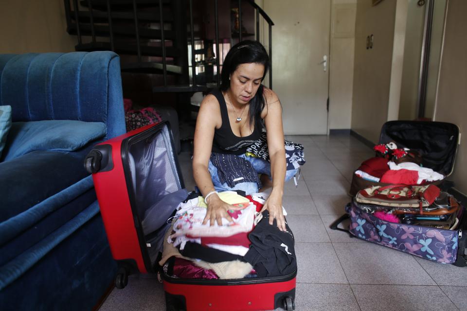 In this Oct. 31, 2019 photo, Yenika Calderon, 41, packs a suitcase with personal items to sell at a secondhand market in an effort to make enough money leave the country, in Caracas, Venezuela. Calderon has spent the past few Sundays haggling with customers over prices for her favorite handbags and her son’s baby clothes. “There are no options for him here,” Calderon said. “I want to be able to go to the supermarket and get the best milk for my son. Here, I can’t.” (AP Photo/Ariana Cubillos)