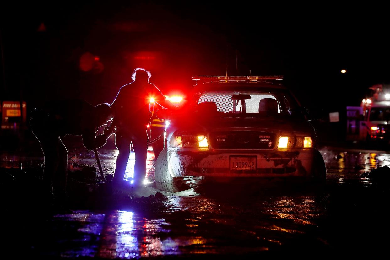 In this Saturday, Jan 5, 2019, photo sheriff's deputies work to free their patrol cruiser from mud covering a stretch of Pacific Coast Highway in Malibu, Calif. A winter storm unleashed mudslides in Southern California wildfire burn areas and trapped motorists on a major highway, and the northern part of the state is bracing for more wet weather. Saturday's deluge loosened hillsides in Malibu where a major fire burned last year, clogging the Pacific Coast Highway with mud and debris.