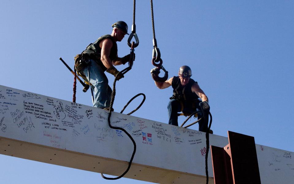 Ironworkers James Brady, left, and Billy Geoghan release the cables from a steel beam after connecting it on the 104th floor of 1 World Trade Center, Thursday, Aug. 2, 2012 in New York. The beam was signed by President Barack Obama with the notes: "We remember," ''We rebuild" and "We come back stronger!" during a ceremony at the construction site June 14. Since then the beam has been adorned with the autographs of workers and police officers at the site. The beam will be sealed into the structure of the tower, which is scheduled for completion in 2014. (AP Photo/Mark Lennihan)