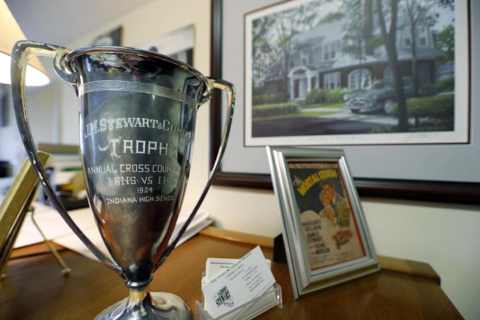 In this photo made on Friday, Dec. 20, 2013, a trophy that was awarded by the hardware store that the father of Hollywood legend Jimmy Stewart owned, sits on the desk of Timothy Harley, executive director of the Jimmy Stewart Museum, in front of a portrait of the house where Stewart grew up, in Indiana, Pa. (AP Photo/Keith Srakocic)