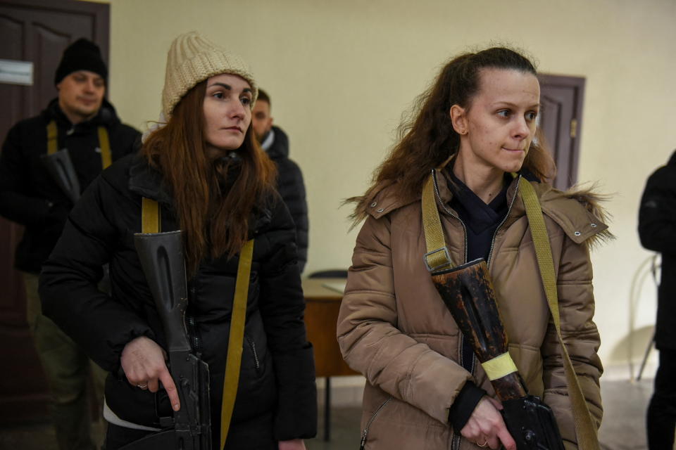 Two civilian women hold rifles as they receive weapons training.