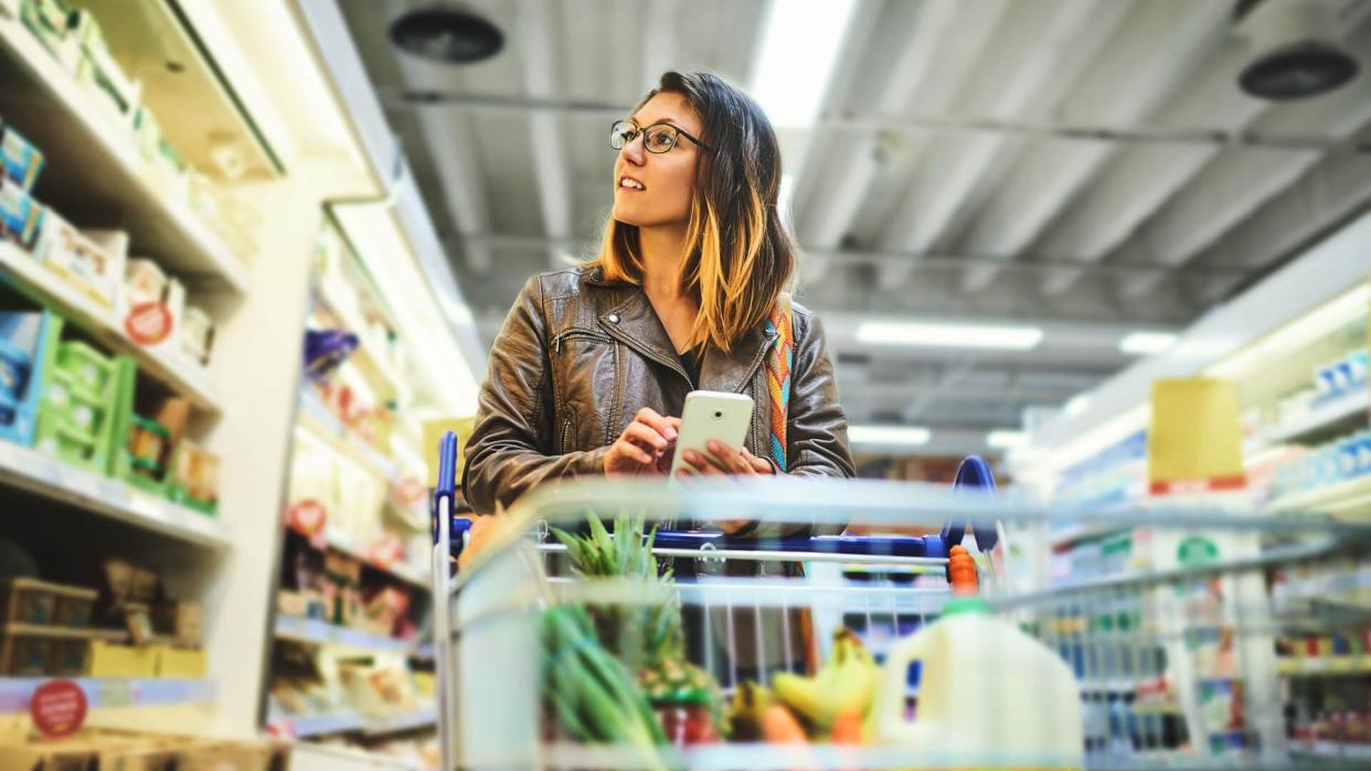 young woman using a mobile phone in a grocery store