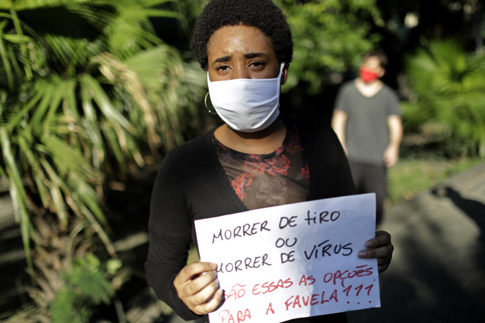 A woman holds a sign that reads in Portuguese "Dying from a shot or dying from a virus. Are those the options for the favela?" during a protest against crimes committed by the police against black people in the favelas, outside the Rio de Janeiro's state government, Brazil, Sunday, May 31, 2020. The protest, called "Black lives matter," was interrupted when police used tear gas to disperse people. "I can't breathe", said some of the demonstrators, alluding to the George Floyd's death. (AP Photo/Silvia Izquierdo)