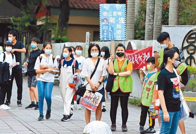 國中會考15日登場，因新冠肺炎疫情升溫，採取高規格防疫措施，不開放陪考，補習班工作人員在門口手持標語，為考生加油。（張鎧乙攝）