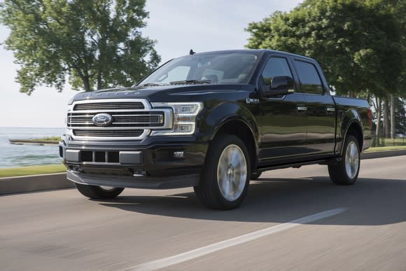 A black 2019 Ford F-150 Limited, a luxurious full-size pickup, on a coastal road.