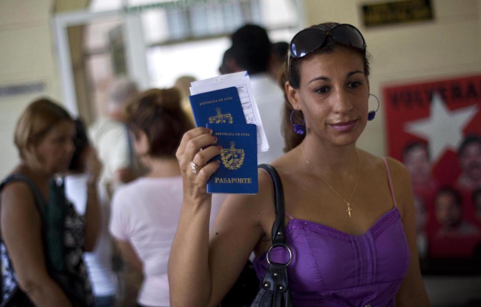A woman shows her passport and that of her son to reporters as she leaves an immigration office in Havana, Cuba, Tuesday, Oct 16, 2012. The Cuban government announced Tuesday that it will no longer require islanders to apply for an exit visa, eliminating a much-loathed bureaucratic procedure that has been a major impediment for many seeking to travel overseas for more than a half-century. (AP Photo/Ramon Espinosa)