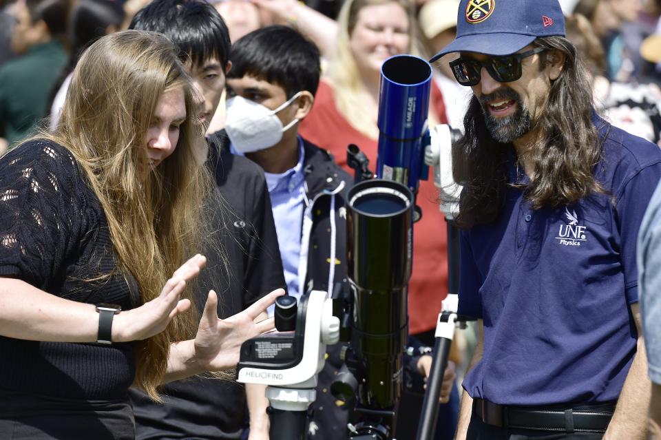 Victoria Martin, an assistant professor of physics, and Chris Kelso, an associate professor of physics, adjust the tracking mechanism of a telescope being used to watch the partial solar eclipse during UNF's watch party Monday.