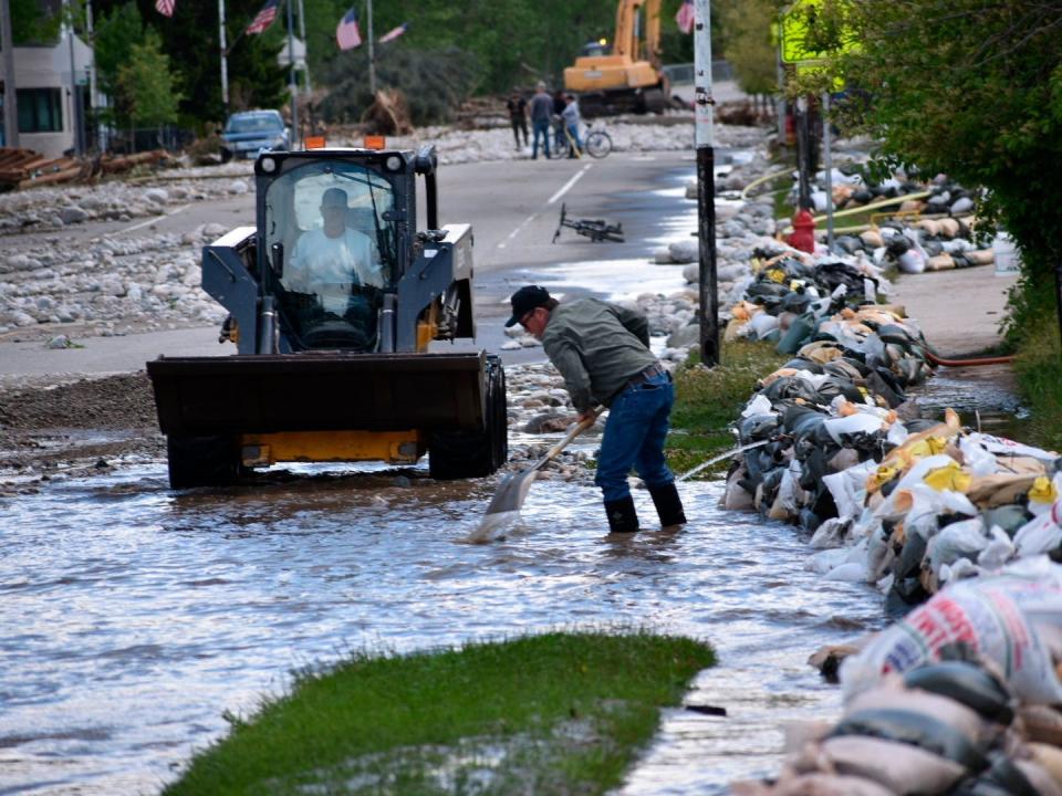 people with truck and shovel scoop water mud debris from a city street