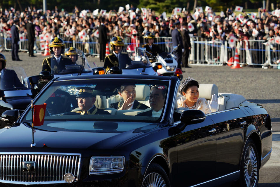 Japanese Emperor Naruhito, center, and Empress Masako, right, smiles during the royal motorcade in Tokyo, Sunday, Nov. 10, 2019.(AP Photo/Eugene Hoshiko)