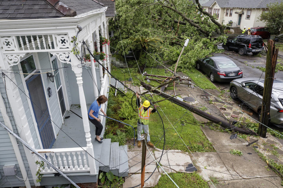 A utility worker helps a resident get through twisted wires and broken poles after powerful storms rolled through the city overnight, in New Orleans Wednesday, May 12, 2021. (David Grunfeld/The Advocate via AP)