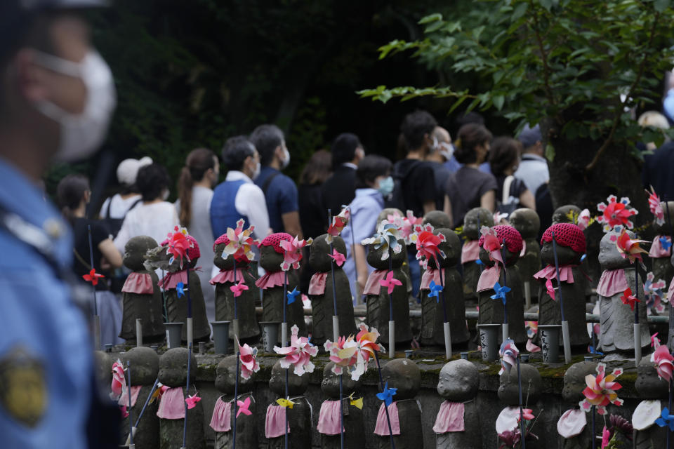 People wait in line along Buddhist guardian deities of travelers and children before their prayers to pay respect for former Japanese Prime Minister Shinzo Abe at Zojoji temple before his funeral in Tokyo on Tuesday, July 12, 2022. Abe was assassinated Friday while campaigning in Nara, western Japan. (AP Photo/Hiro Komae)